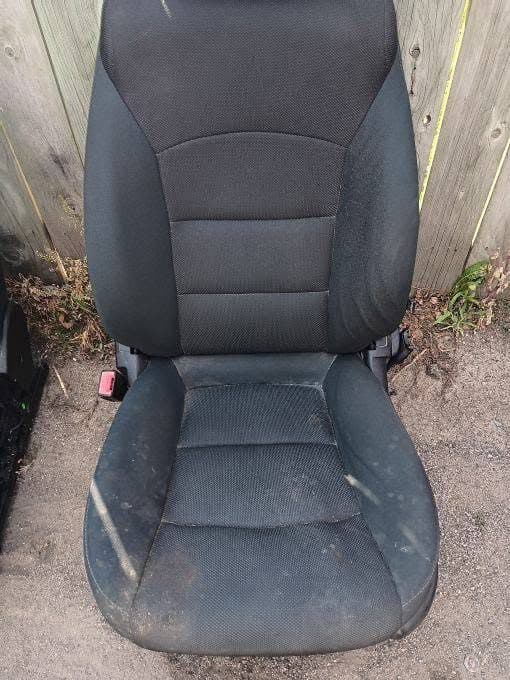 Stained black fabric car seat before professional upholstery cleaning